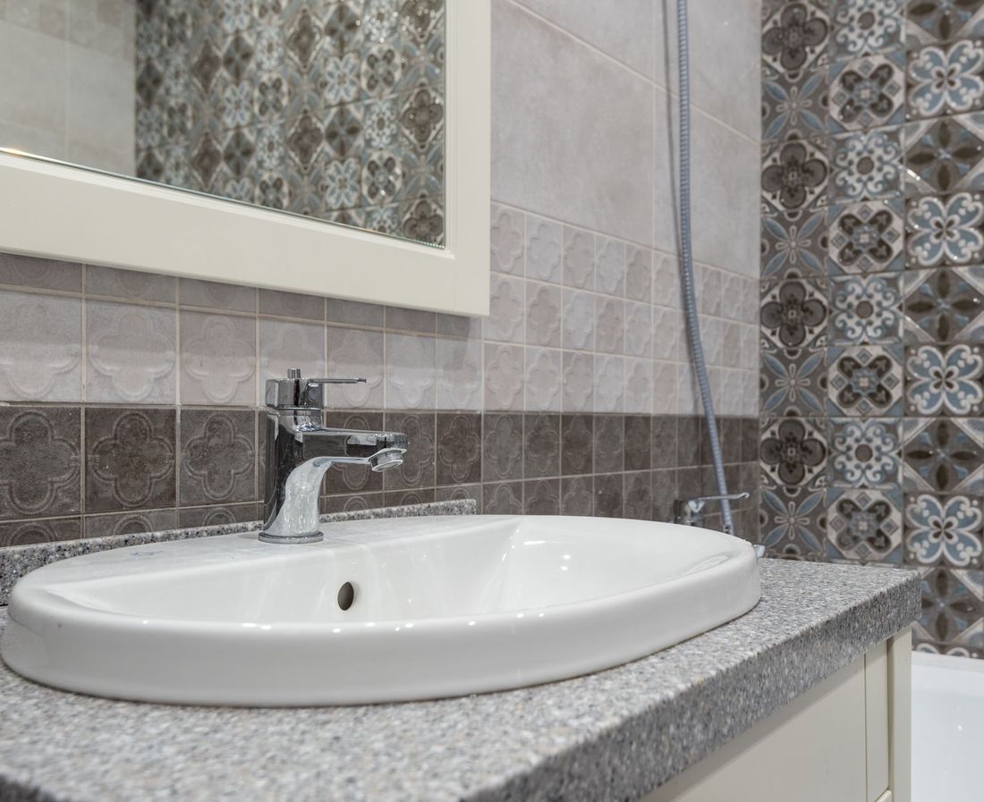 A white basin and tap against patterned tiles