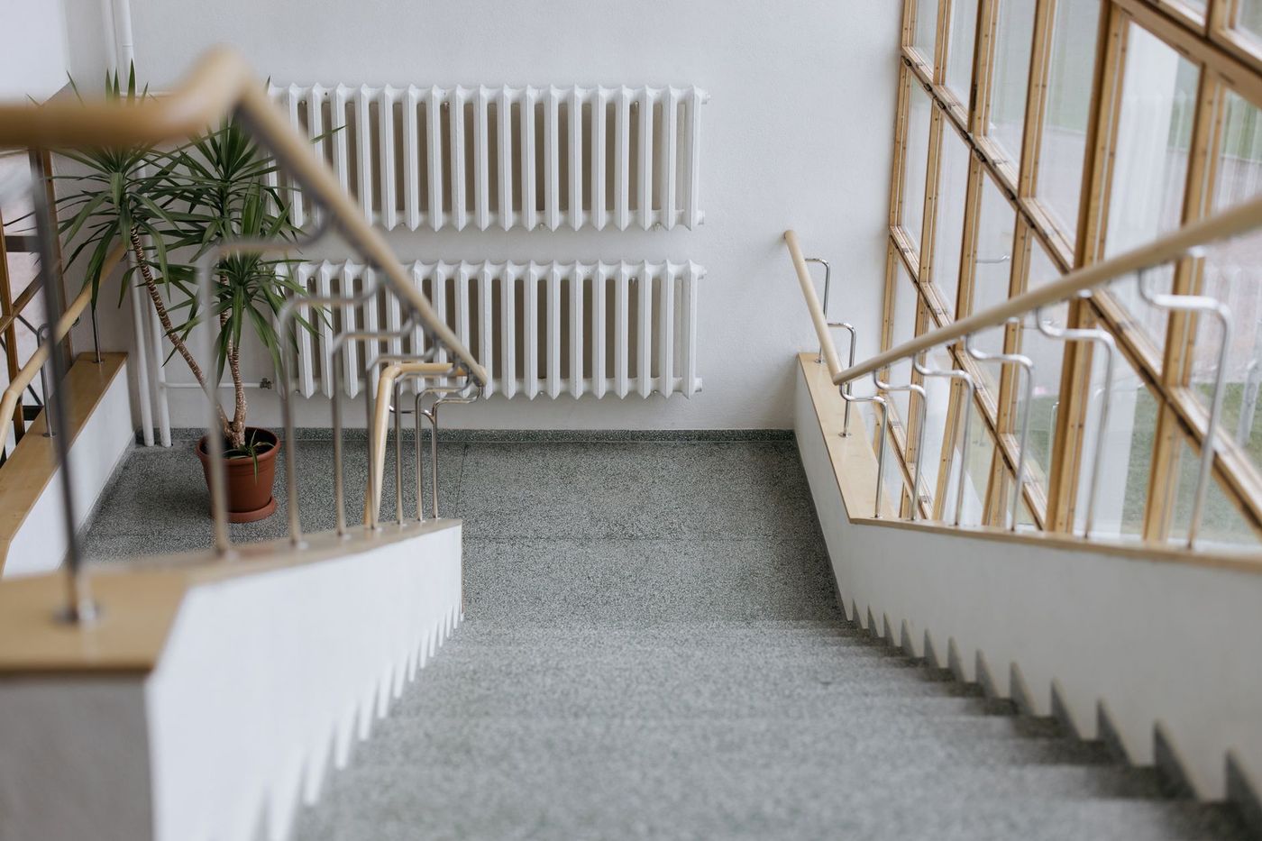 A white radiator on a landing wall beside a staircase