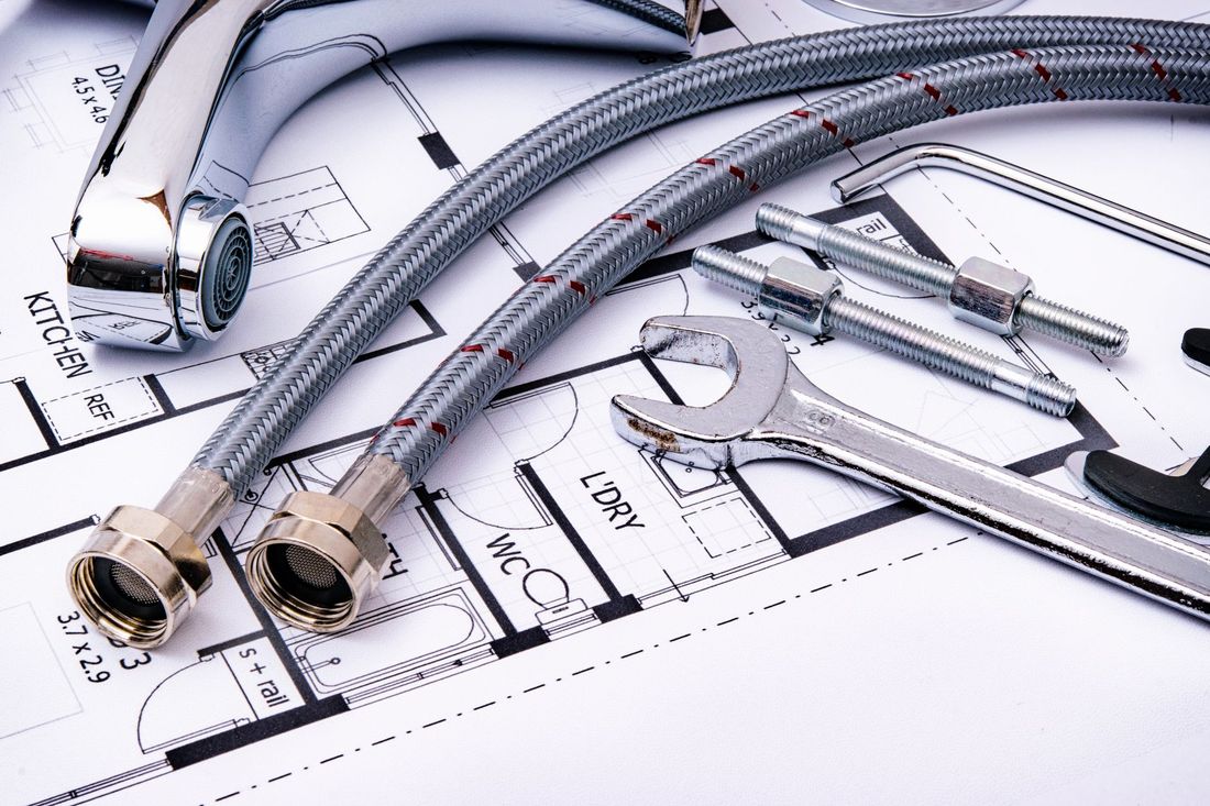 A tap, braided hoses and a wrench laid out on a floor plan